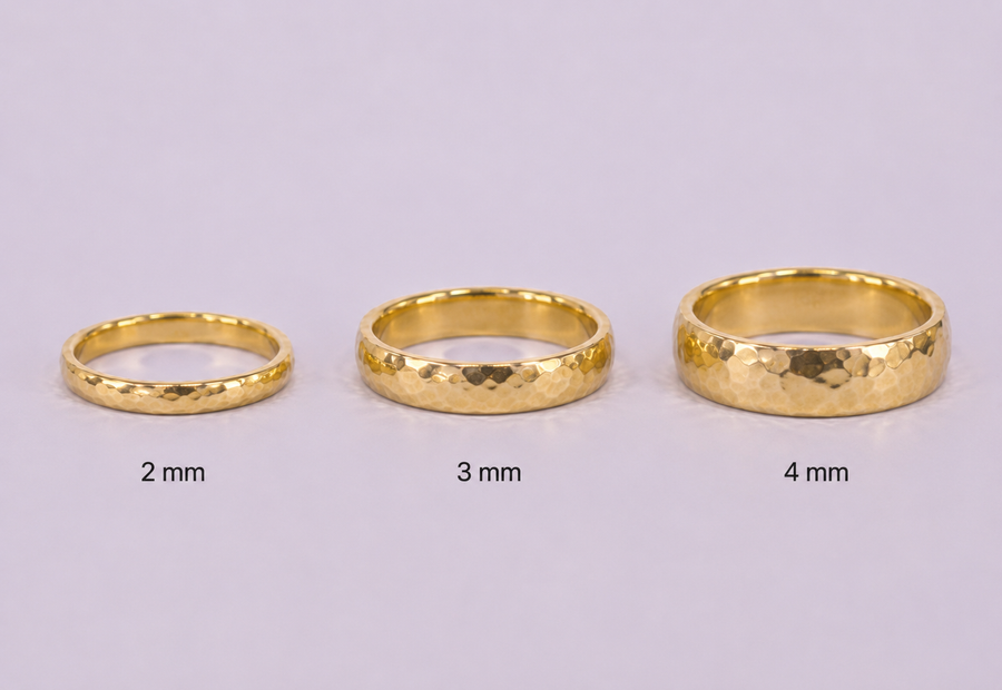 Three gold rings of different thicknesses on a light gray background